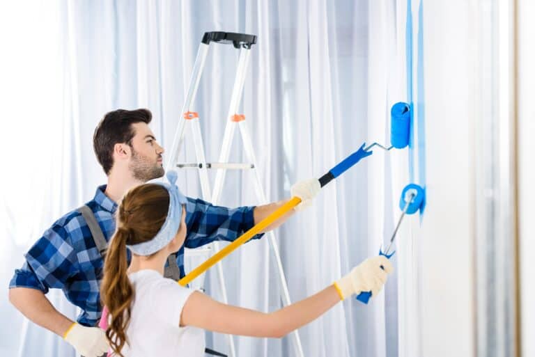 boyfriend and girlfriend painting wall with blue paint 768x513 1