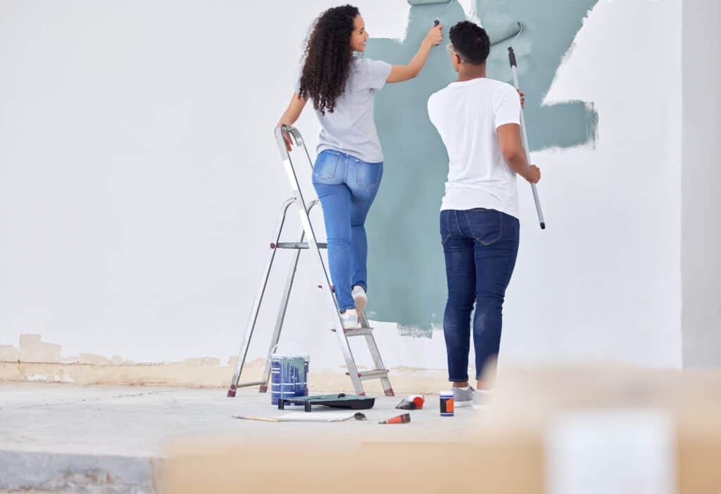 shot of a young couple painting a wall in a room together 1024x702 1